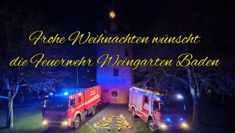 Es ist der Wartturm zusehen, davor stehen zwei Einsatzfahrzeuge, dazwischen sind Schläuche in Form eines Tannenbaumes gelegt und mit Warnleuchten als Schmuck versehen. Darüber ist die Beschriftung 